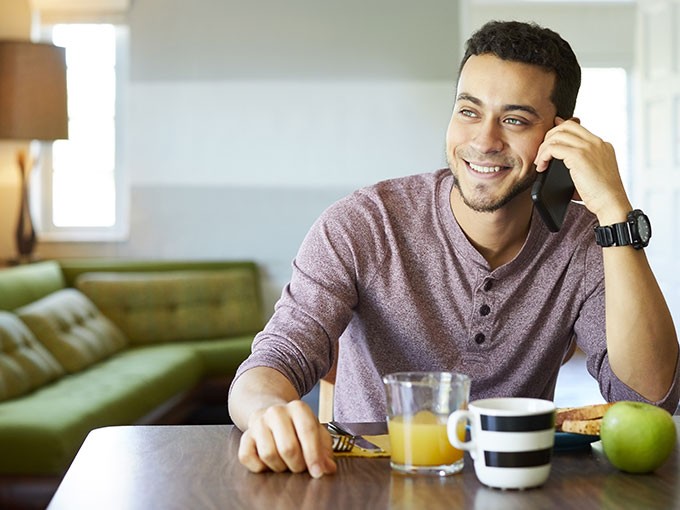 Man talking on phone at kitchen table during breakfast