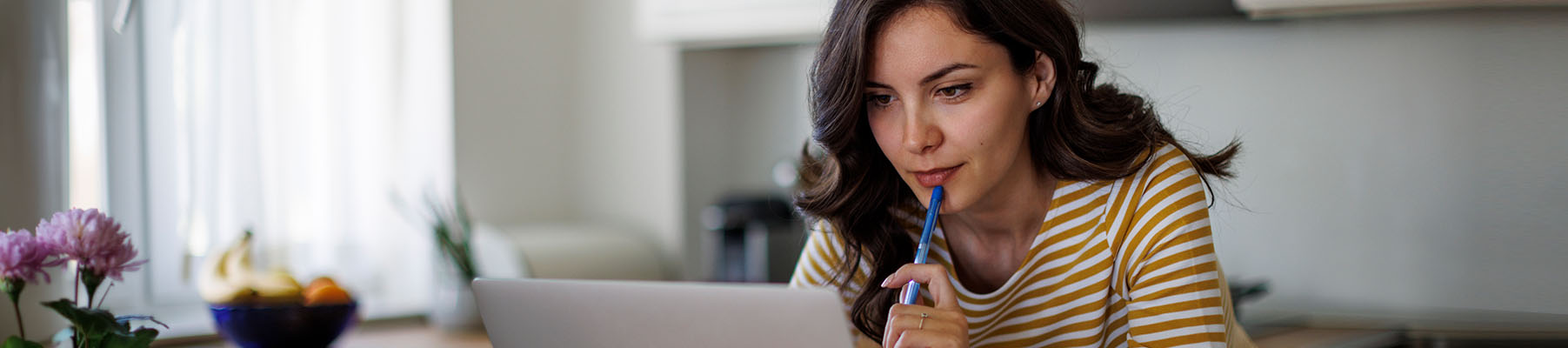 A middle aged woman thinking while she is working on a laptop computer.