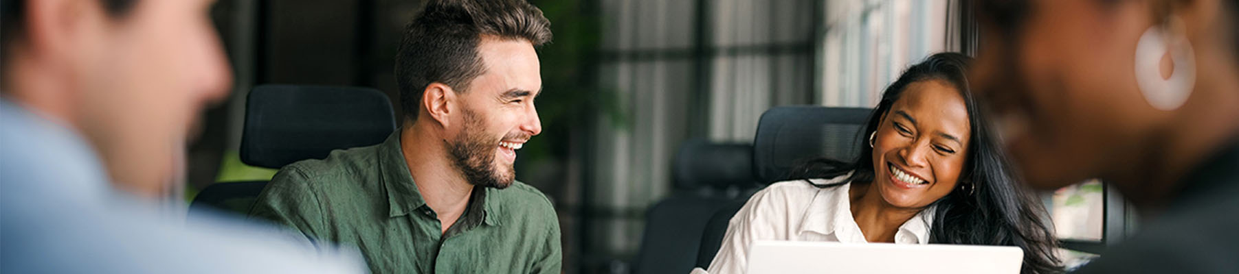 Young business people laughing in a business meeting around a small table.