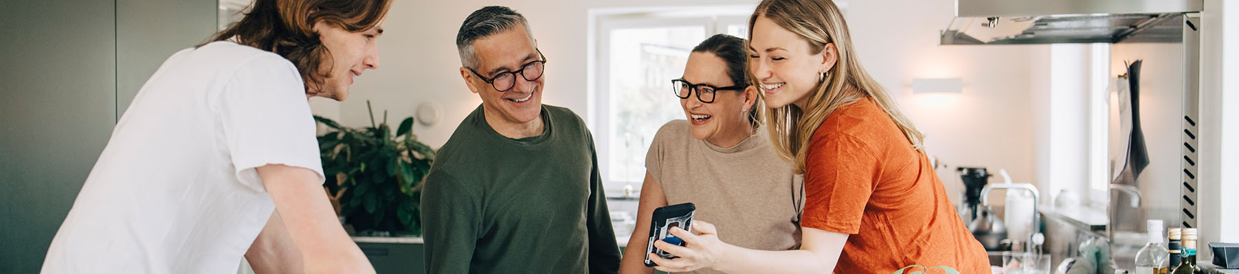 A happy young woman showing her family something on her phone