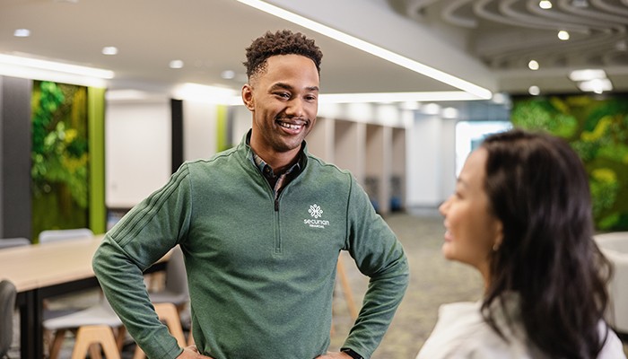 Two Securian Financial associates laughing and talking in a branded commons area on campus