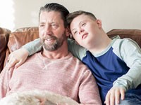 Father, son and dog watching TV on a couch